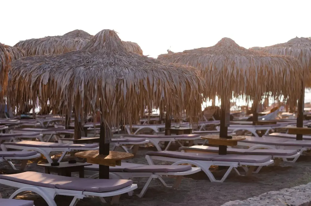 Rows of straw umbrellas and white sunbeds on the sand