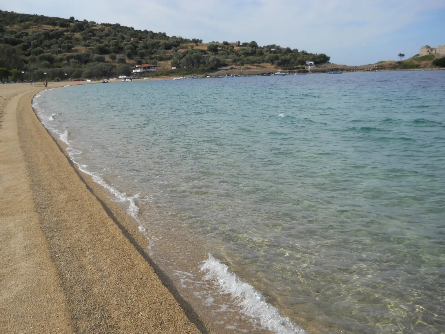 Η μακριά αμμουδιά της Τορώνης που καμπυλώνει προς το ακρωτήρι, με διάφανα ρηχά νερά